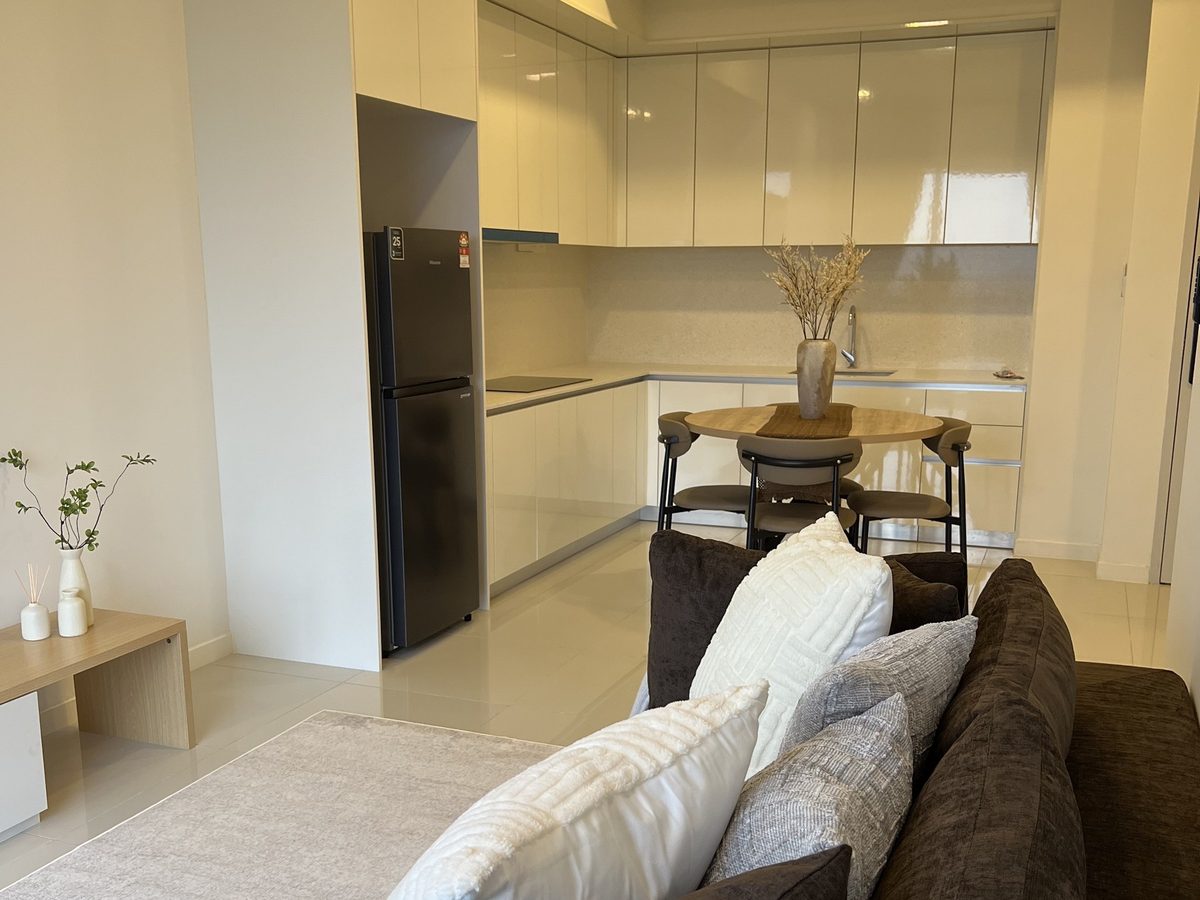 Kitchen with cream cabinets and fridge, round oak dining table and the sofa in the foreground