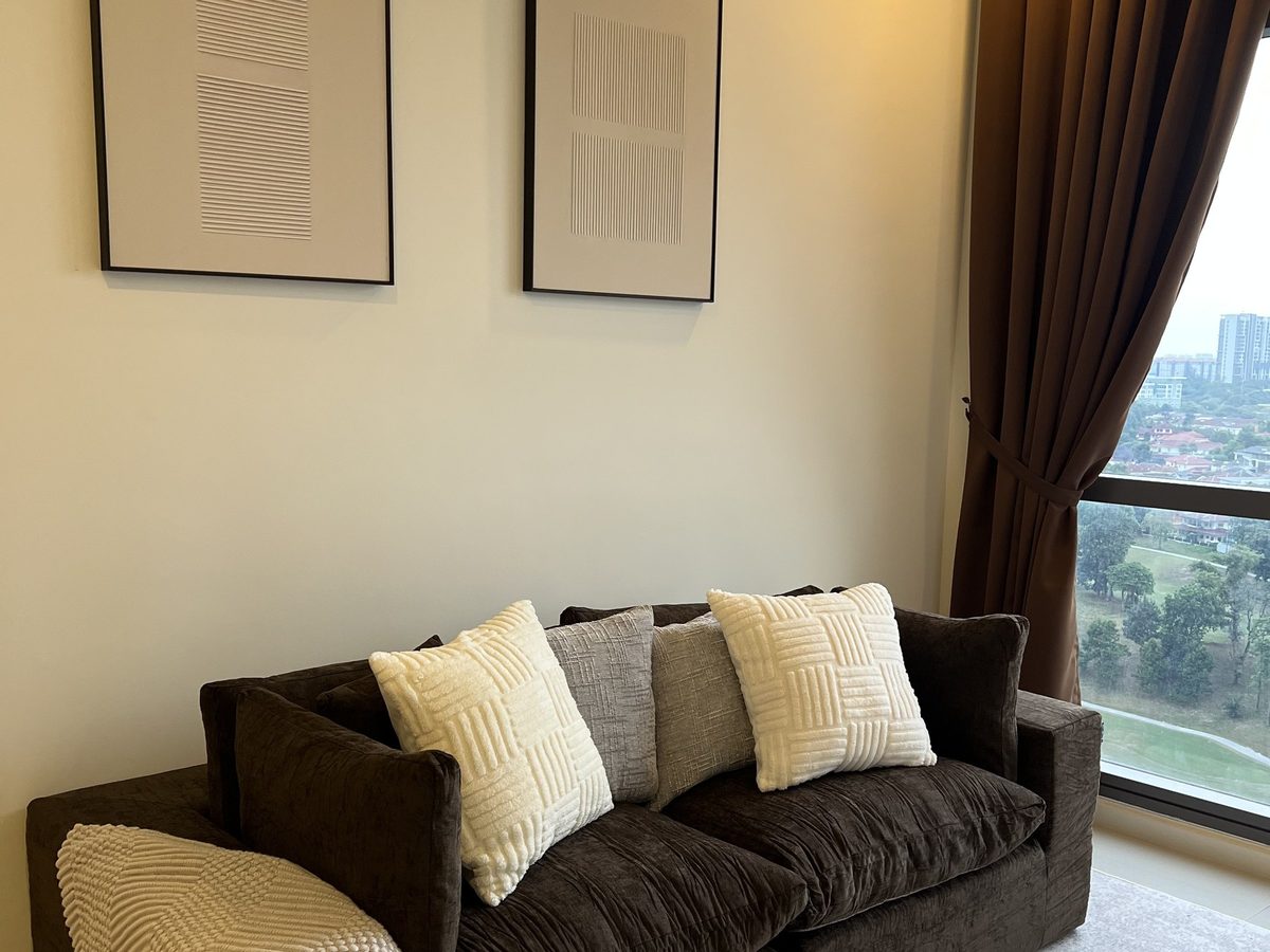Charcoal sofa with cream and grey cushions beneath two framed prints, window and view beside