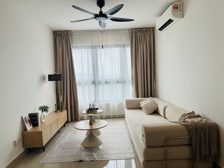 The furnished living room at M Vertica, Cheras — cream sofa, oak media console and layered curtains